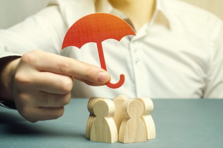 Boss holding a red umbrella and defending his team with a gesture of protection. Life insurance. Customer care, care for employees. Security and safety in a business team. Selective focus